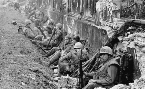 A Unit Of The 1St Battalion 5Th Marine Regiment Rests Alongside A Battered Wall Of Hue S