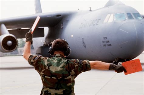 A Us Air Force Crew Chief Directs A C 141 Starlifter To The Taxi Way For Deployment The